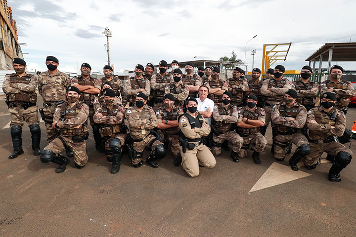 presidente Bolsonaro ajoelhado e de braços cruzados junto a grupo de policiais militares de Minas Gerais.